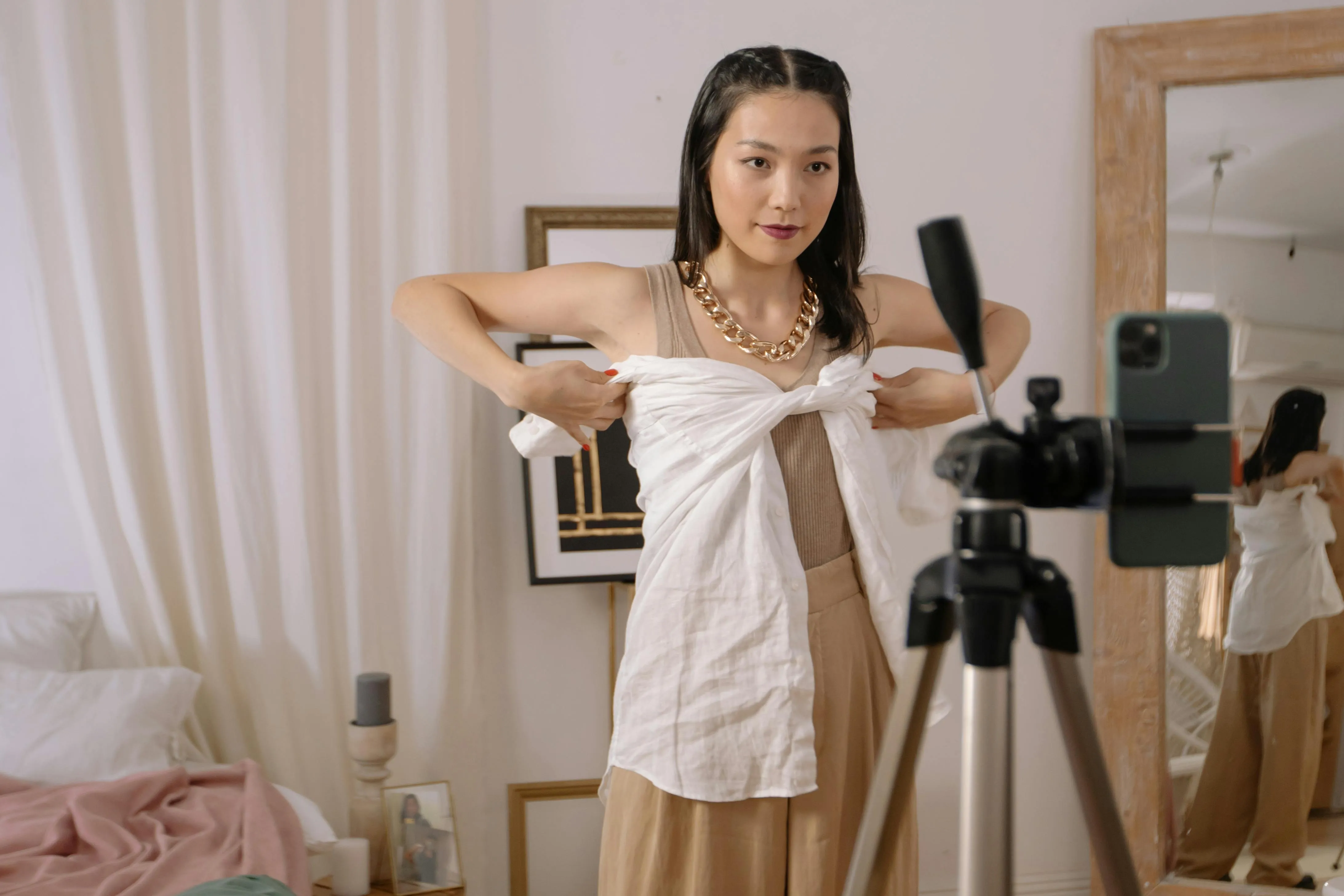 A female content creator filming a fashion tutorial video on their smartphone.